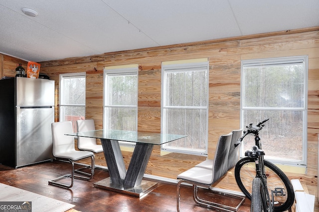 dining room with dark hardwood / wood-style flooring and wood walls