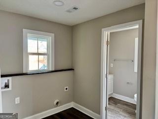 clothes washing area with electric dryer hookup and hardwood / wood-style flooring