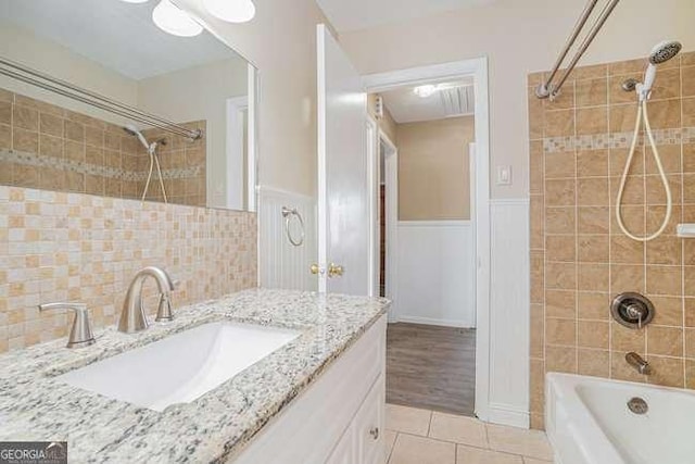 bathroom with tile patterned flooring, tiled shower / bath, and vanity