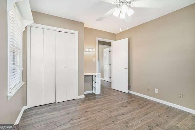 unfurnished bedroom with light hardwood / wood-style floors, a closet, and ceiling fan