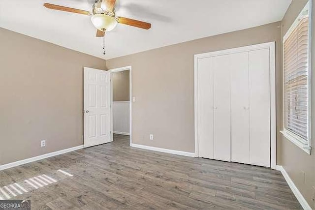 unfurnished bedroom with wood-type flooring, a closet, and ceiling fan