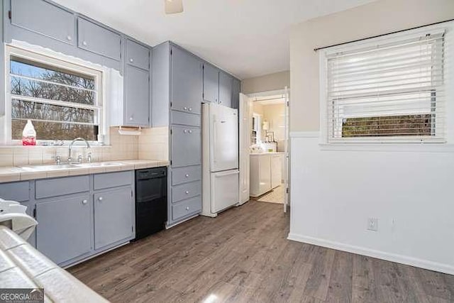 kitchen with sink, dark hardwood / wood-style floors, black dishwasher, tile counters, and white fridge