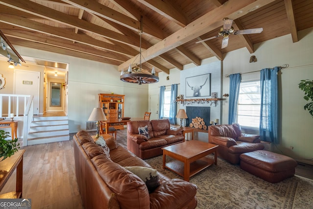 living room with lofted ceiling with beams, ceiling fan with notable chandelier, hardwood / wood-style floors, and wooden ceiling