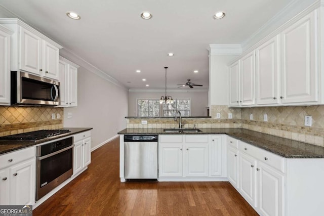 kitchen with sink, hanging light fixtures, appliances with stainless steel finishes, kitchen peninsula, and white cabinets