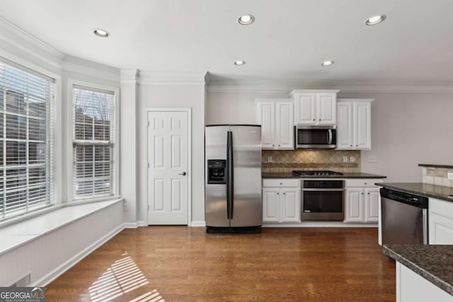 kitchen featuring appliances with stainless steel finishes, dark stone countertops, white cabinets, and dark hardwood / wood-style flooring