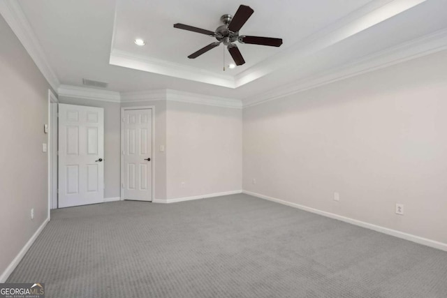 carpeted spare room with a raised ceiling, ornamental molding, and ceiling fan