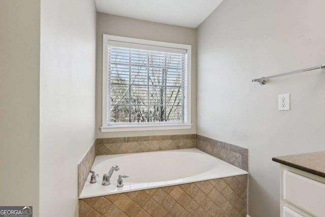 bathroom featuring vanity and tiled bath