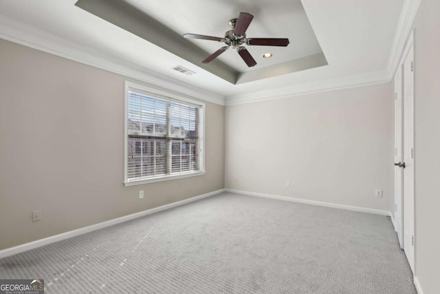 empty room featuring light carpet, ornamental molding, a raised ceiling, and ceiling fan