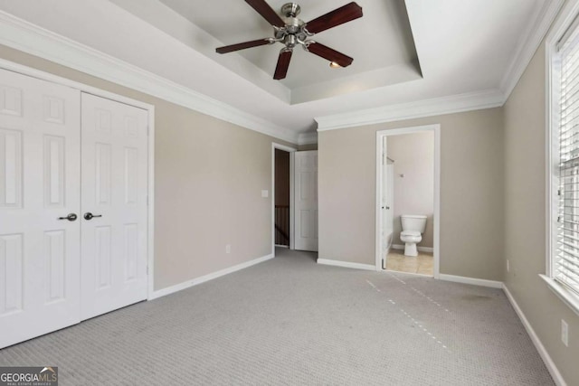 unfurnished bedroom with connected bathroom, crown molding, light carpet, a raised ceiling, and a closet