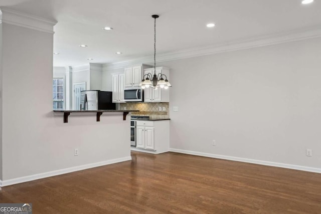 kitchen featuring pendant lighting, a breakfast bar, appliances with stainless steel finishes, backsplash, and white cabinets