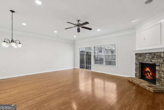 unfurnished living room with hardwood / wood-style flooring, a fireplace, ornamental molding, and ceiling fan with notable chandelier