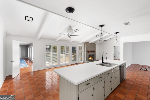 kitchen featuring sink, dishwasher, ceiling fan, a fireplace, and a kitchen island with sink