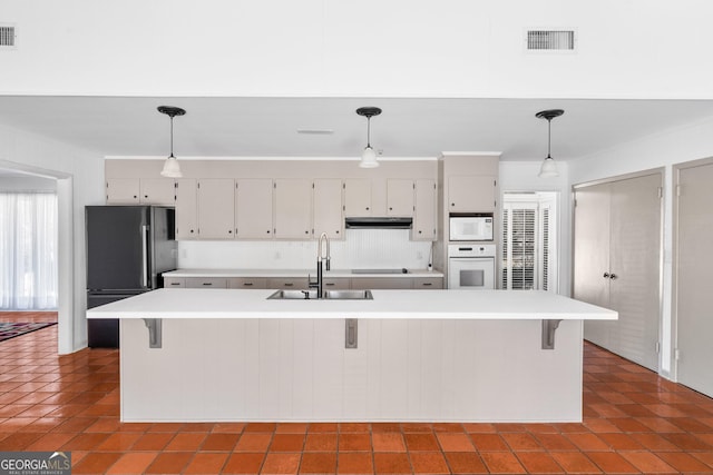 kitchen with pendant lighting, sink, black appliances, and an island with sink