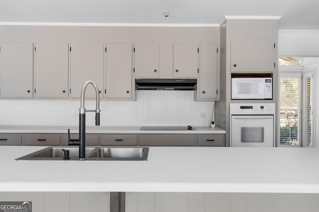 kitchen featuring white cabinetry, crown molding, sink, and white appliances