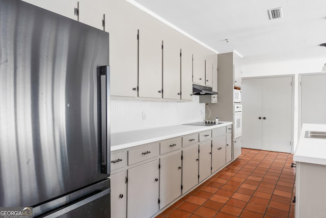 kitchen featuring white appliances, ornamental molding, dark tile patterned flooring, and white cabinets