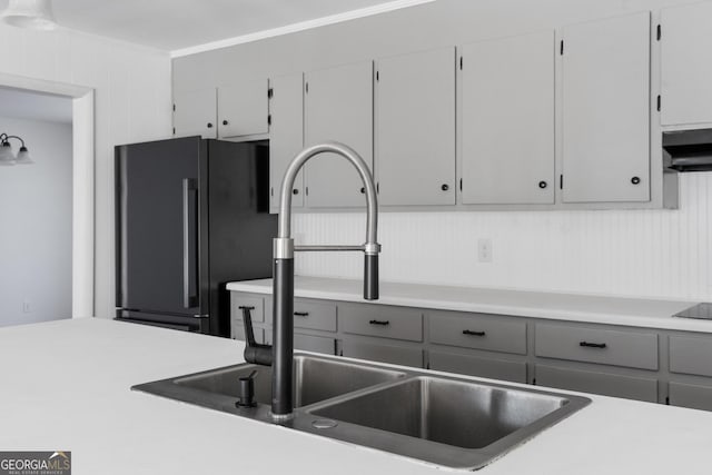 kitchen featuring black fridge, crown molding, sink, and gray cabinetry