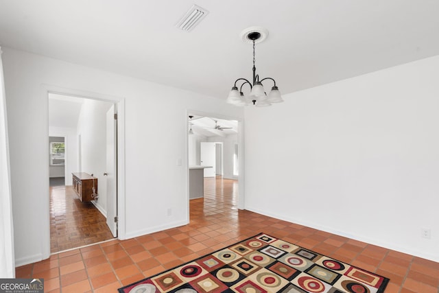 unfurnished dining area featuring tile patterned floors and ceiling fan with notable chandelier