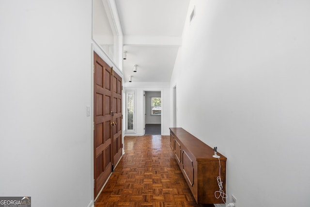 corridor featuring a towering ceiling and dark parquet floors