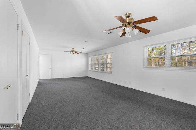 empty room with ceiling fan and dark colored carpet