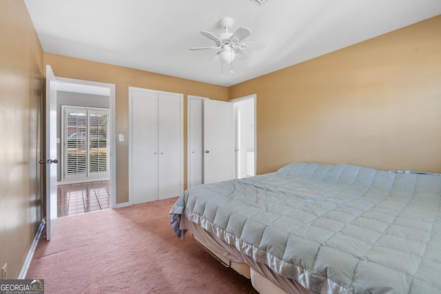 carpeted bedroom featuring ceiling fan and two closets