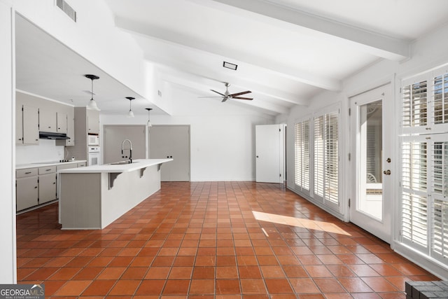 kitchen featuring sink, gray cabinetry, hanging light fixtures, a kitchen breakfast bar, and black electric stovetop