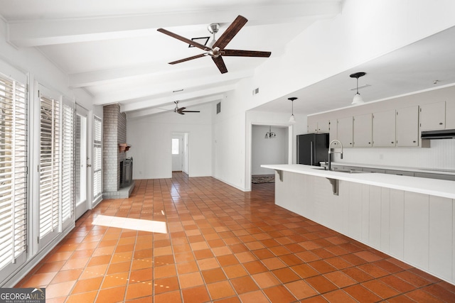 kitchen featuring sink, decorative light fixtures, a kitchen breakfast bar, a fireplace, and black appliances