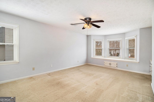 unfurnished room featuring ceiling fan, light colored carpet, and a textured ceiling