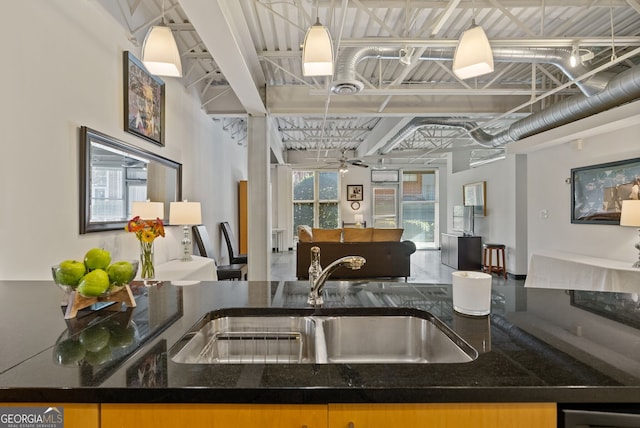 kitchen with sink, hanging light fixtures, dark stone counters, and ceiling fan