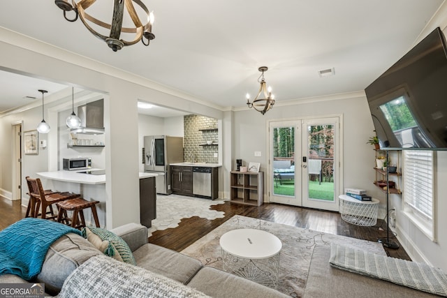 living room with crown molding, plenty of natural light, hardwood / wood-style floors, and a notable chandelier