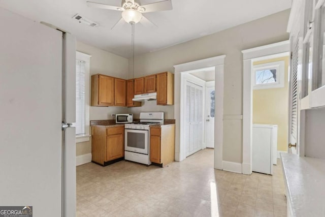 kitchen with white appliances, washer / dryer, and ceiling fan