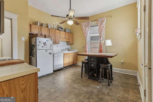 kitchen with ceiling fan, white appliances, a breakfast bar, and sink