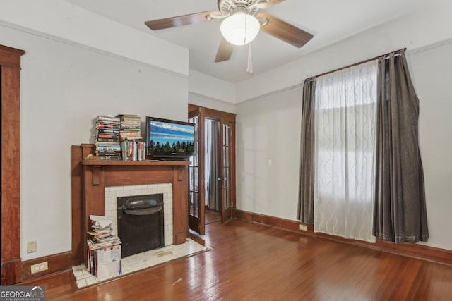 unfurnished living room with hardwood / wood-style flooring, a brick fireplace, and ceiling fan