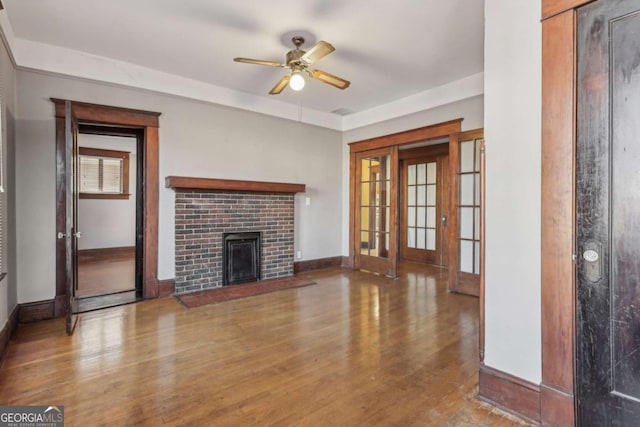 unfurnished living room with hardwood / wood-style flooring, ceiling fan, and a brick fireplace