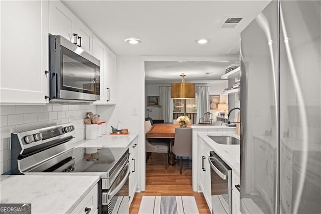 kitchen featuring sink, light stone countertops, white cabinets, and appliances with stainless steel finishes