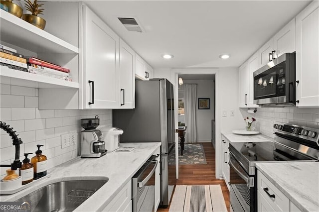 kitchen featuring light stone countertops, white cabinetry, appliances with stainless steel finishes, and sink