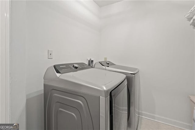 laundry area with light tile patterned floors and washing machine and clothes dryer