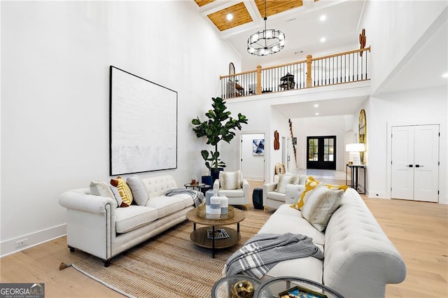 living room featuring an inviting chandelier, hardwood / wood-style floors, a high ceiling, and beamed ceiling