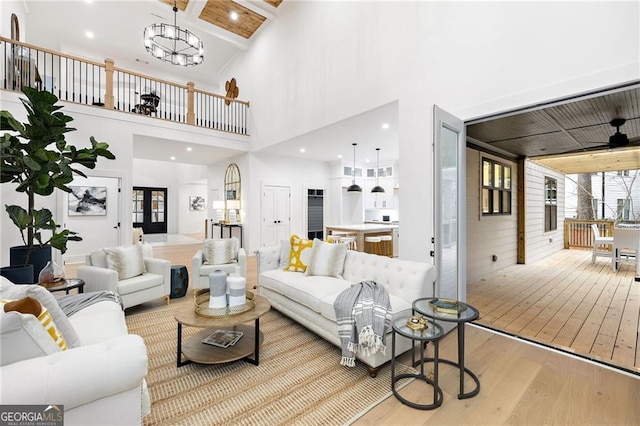 living room featuring a towering ceiling, an inviting chandelier, and light hardwood / wood-style flooring