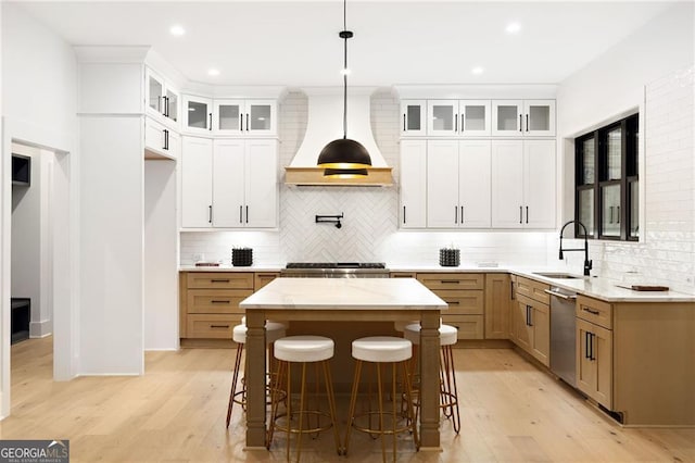 kitchen with white cabinetry, a center island, sink, and custom exhaust hood