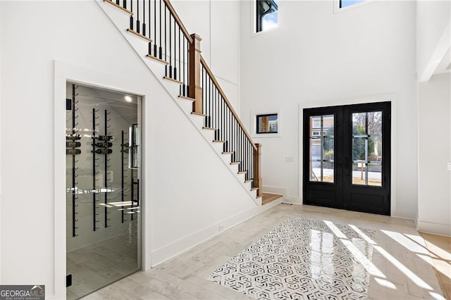 foyer featuring light hardwood / wood-style flooring, french doors, and a high ceiling