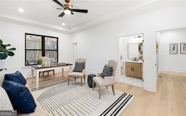 living area featuring ceiling fan, a tray ceiling, sink, and light hardwood / wood-style flooring