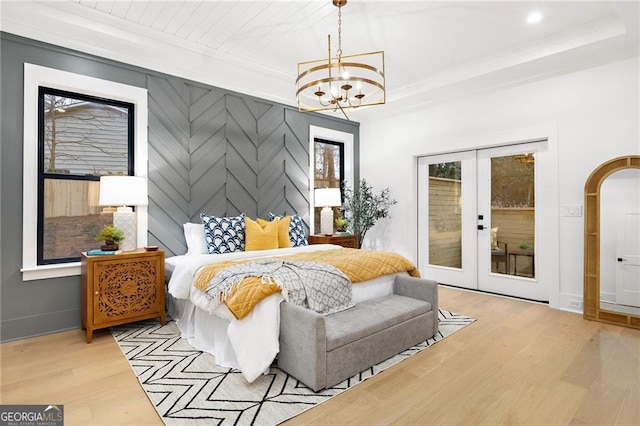 bedroom featuring french doors, an inviting chandelier, light hardwood / wood-style flooring, and access to outside