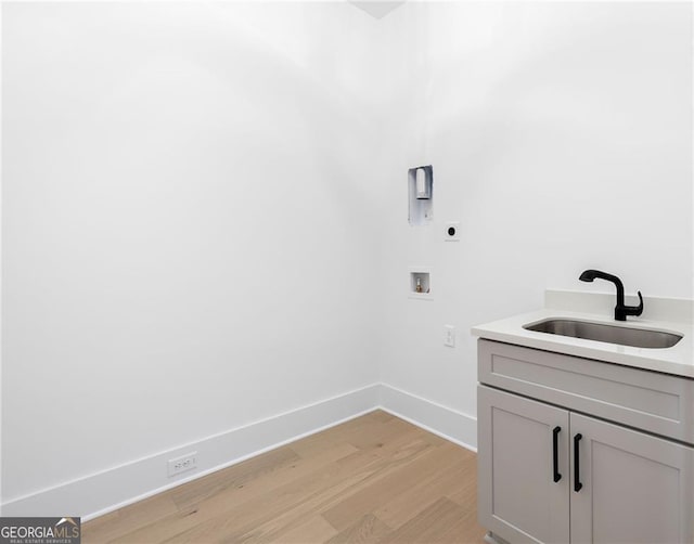 laundry room with sink, electric dryer hookup, hookup for a washing machine, cabinets, and light hardwood / wood-style floors