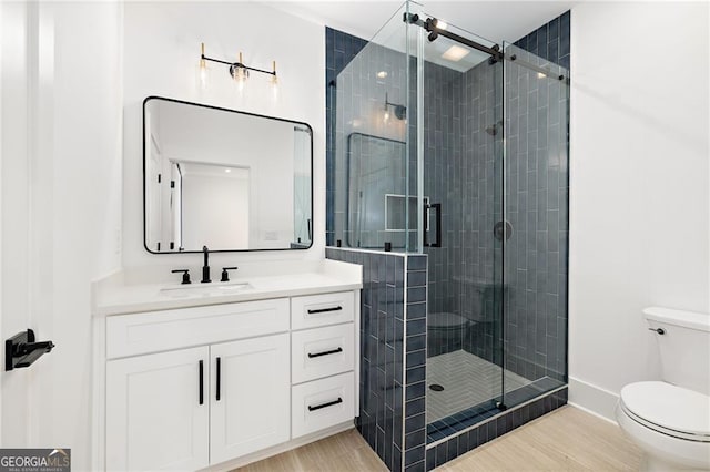 bathroom with vanity, toilet, and a shower with door