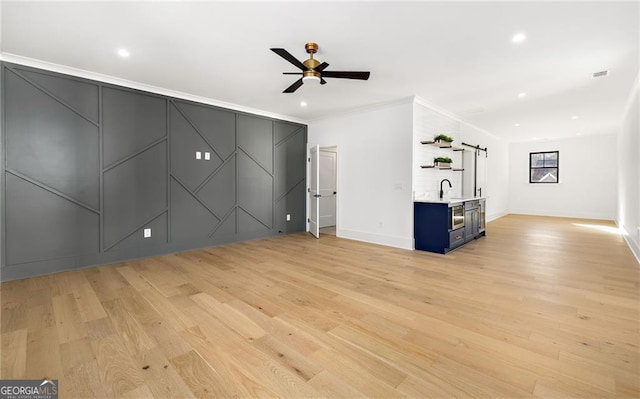 unfurnished living room featuring ceiling fan, ornamental molding, and light hardwood / wood-style flooring