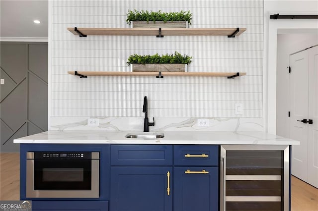 bar featuring blue cabinetry, sink, stainless steel oven, beverage cooler, and light stone countertops