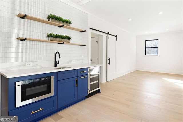 bar with blue cabinets, sink, a barn door, wall oven, and beverage cooler