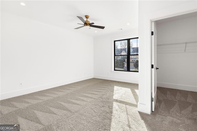 unfurnished bedroom with a walk in closet, carpet, ceiling fan, and a closet