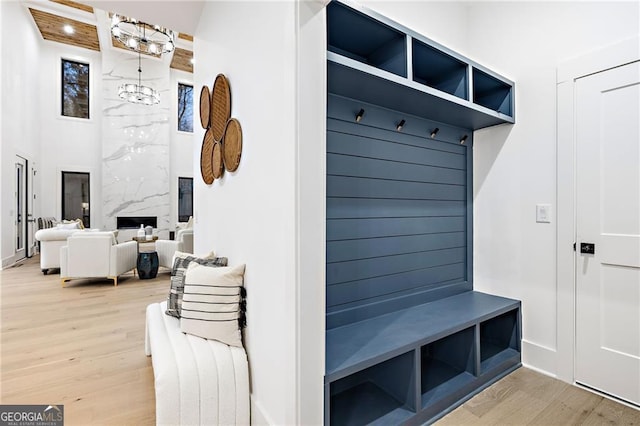 mudroom featuring hardwood / wood-style flooring, a towering ceiling, and an inviting chandelier