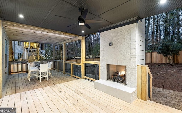 wooden deck featuring an outdoor brick fireplace and ceiling fan